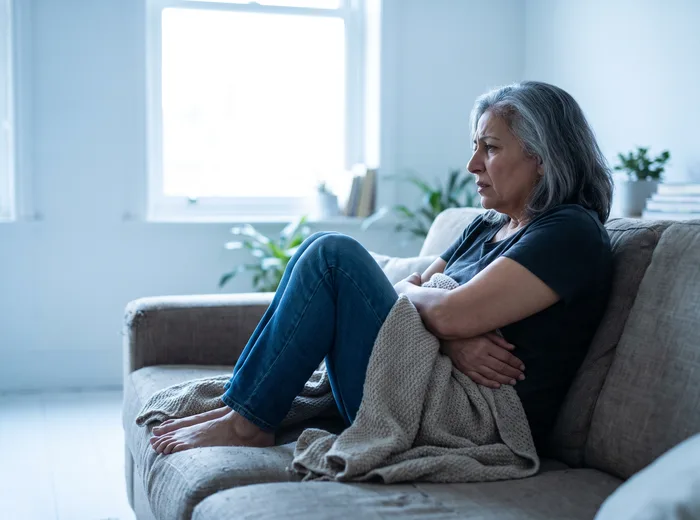 Patient curled up on the couch holding their abdomen in discomfort