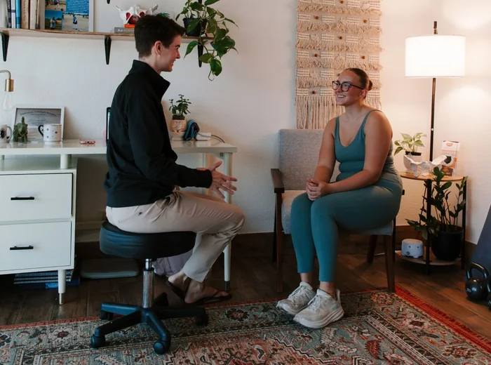 Dr. Hare on a rolling stool talking with a seated patient