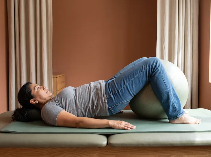 Patient performing a supported bridge exercise on a mat