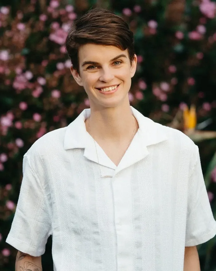 Dr. Sarah Hare smiling outdoors in a white camp collar shirt