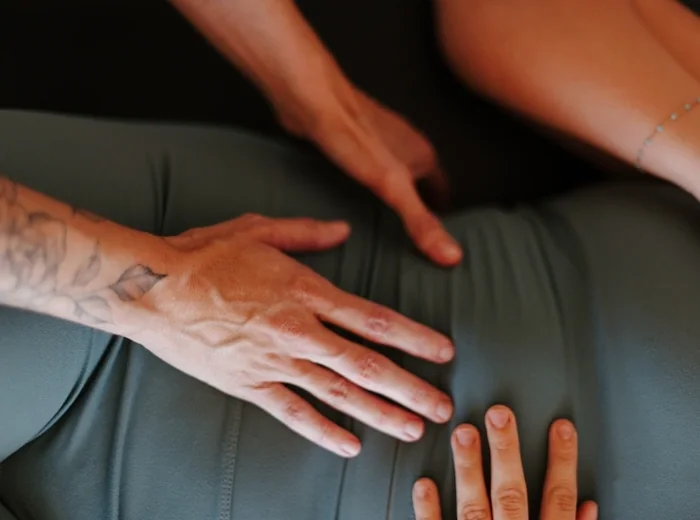 Tattooed hand spread flat across a patient's lower back