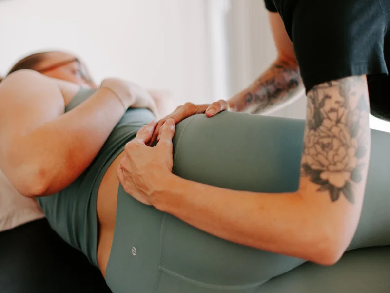 Close view of tattooed hands cupped around a patient's hip and waistband
