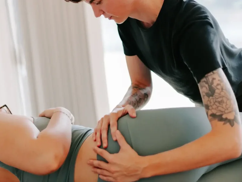 Dr. Hare's tattooed forearms guiding a patient's hip on the treatment table
