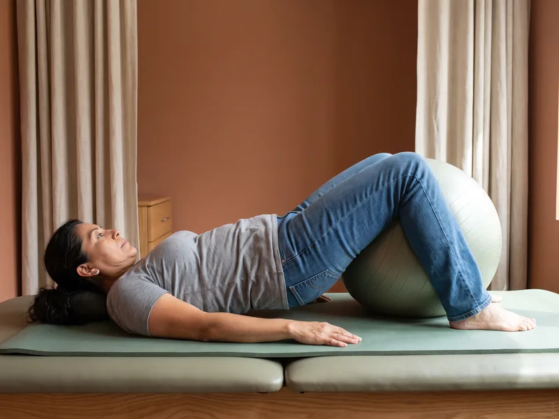 Patient performing a supported bridge exercise on a mat