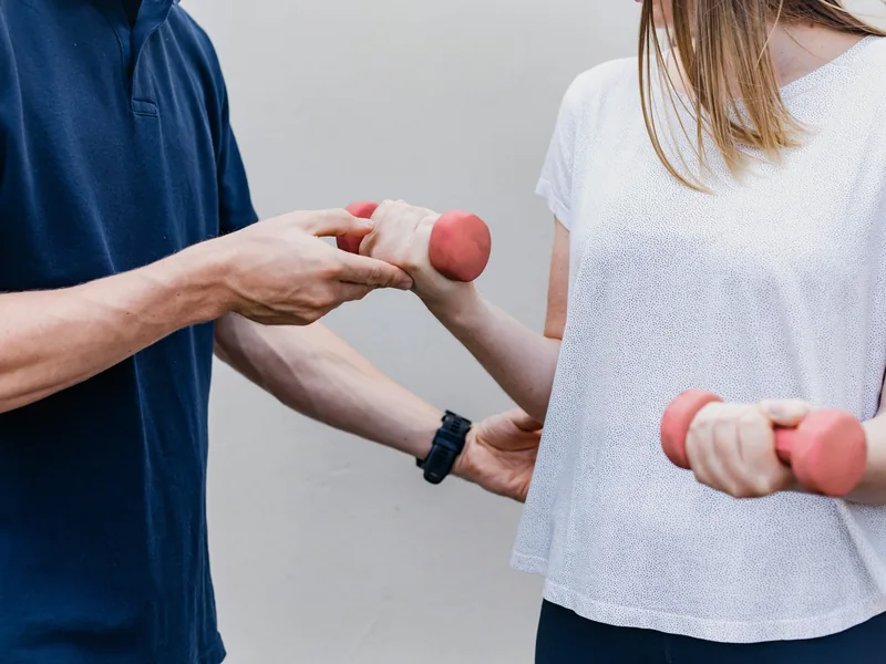 Physical therapist guiding a patient through a dumbbell strengthening exercise