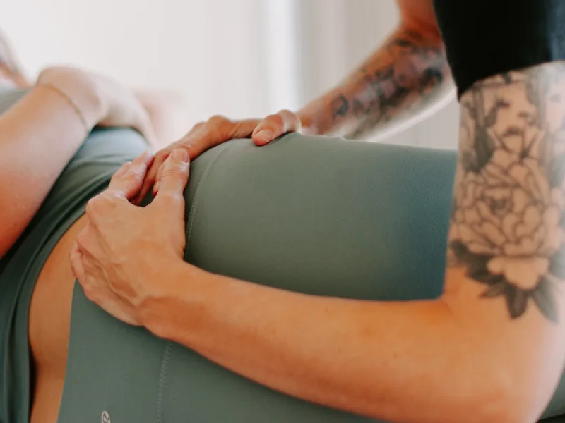 Close crop of two hands working along a patient's hip and lower back