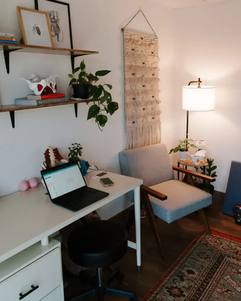 Clinic desk with spine model, macrame hanging and armchair under warm lamplight