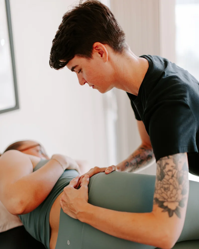 Dr. Hare looking down while both hands assess a side lying patient's hip
